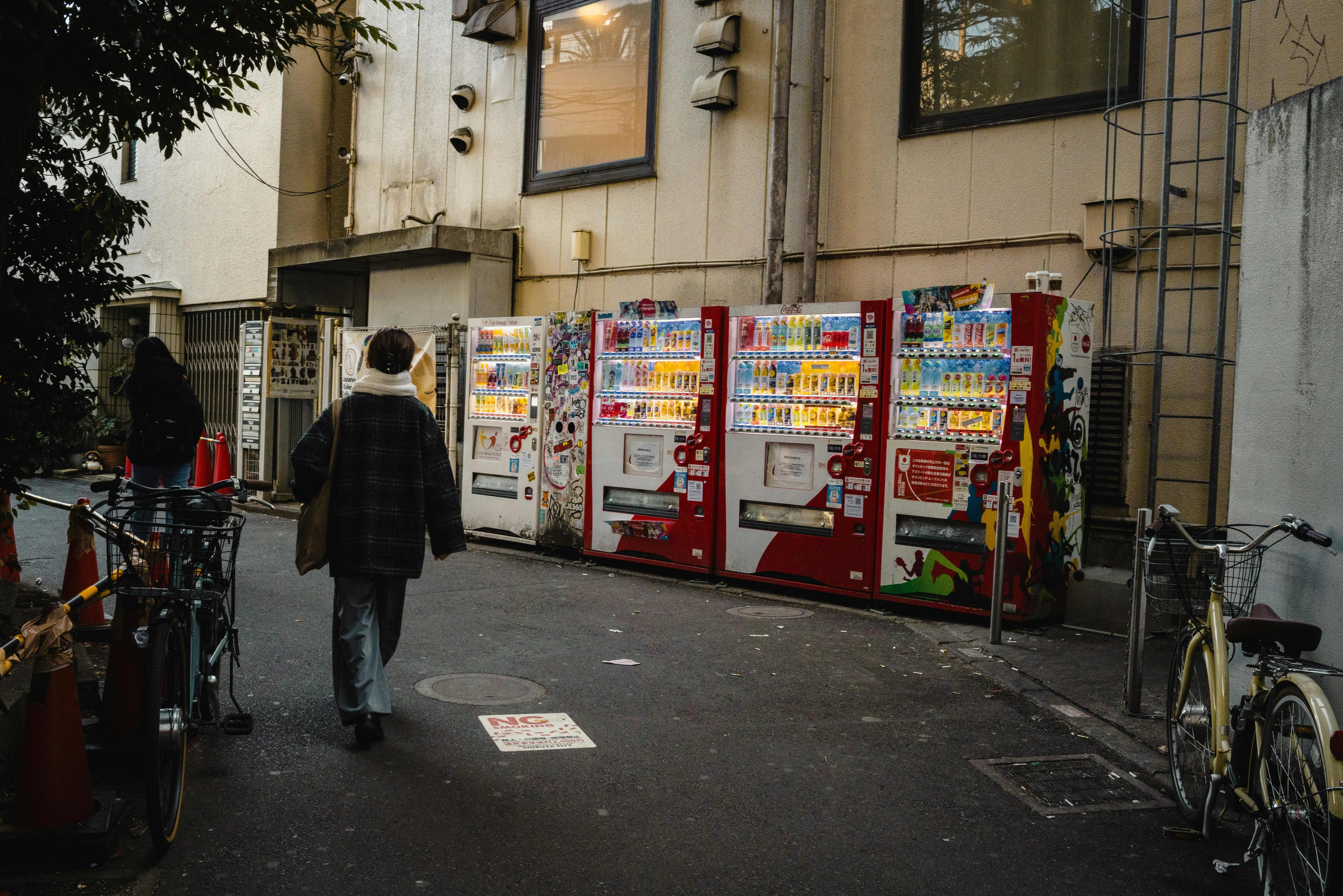 Vibrant Alley: Person Walks Past Illuminated Vending Machines