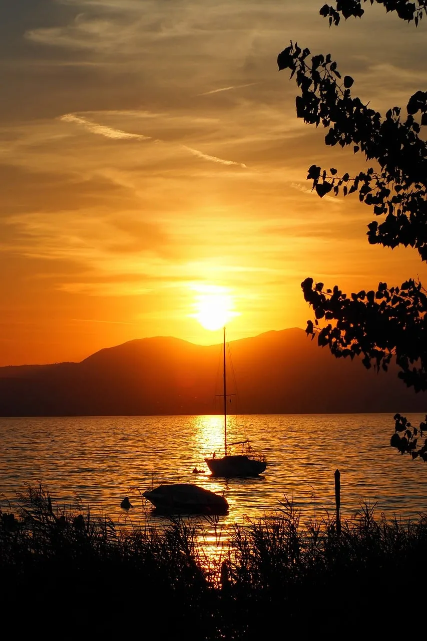 Breathtaking Sunset over Tranquil Lake with Silhouetted Boats